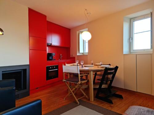 a kitchen with red cabinets and a table with chairs at Casa na Fraga in Aldeia das Dez