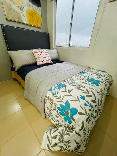 a bedroom with a bed with a flower patterned comforter at LuXe Condo in Iloilo in Iloilo City