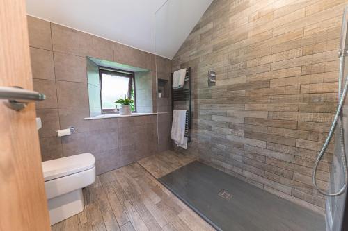 a bathroom with a toilet and a glass shower at Cow Barn, Duddon Bridge in Broughton in Furness