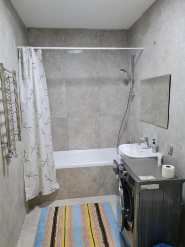 Un baño con cortina de ducha y lavabo. en Апартаменты в новом доме, en Almaty