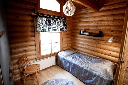 a bedroom in a log cabin with a bed and a window at Kolin Vernetti 3 in Kolinkylä