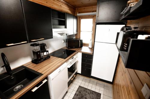 a small kitchen with black cabinets and white appliances at Kolin Vernetti 3 in Kolinkylä