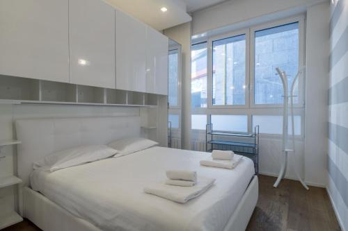 a white bedroom with a large white bed with two towels at Easylife - San Babila - Elegante e rifinito bilocale nel cuore della città in Milan