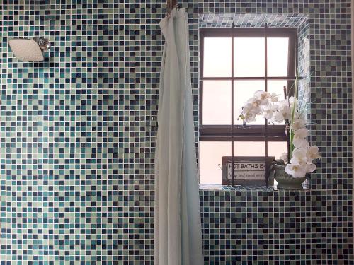 baño con ventana y jarrón de flores en Harbour Delight & Harbour Comfort, en Ciudad del Cabo