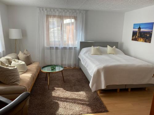 een witte slaapkamer met een bed en een bank bij Schwarzwaldglück Apartment in Oberried