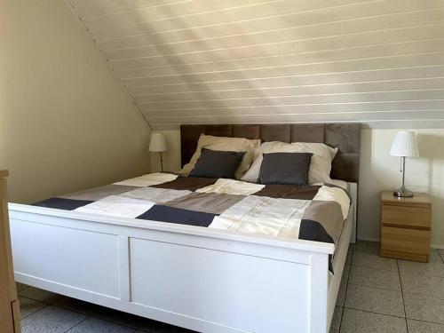 a large white bed in a bedroom with a ceiling at Uroczy domek nad samym morzem in Dębki