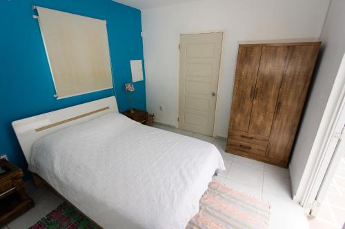 a bedroom with a white bed and a blue wall at Westpunt Beach Apartments in Willemstad