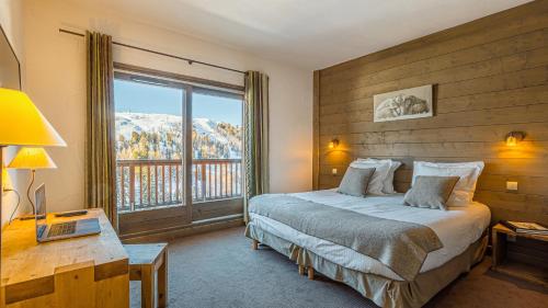 ein Schlafzimmer mit einem Bett und einem großen Fenster in der Unterkunft Hôtel Carlina by Les Etincelles in Belle Plagne