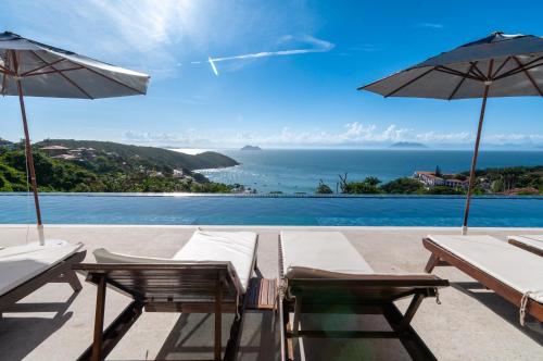 a view of a pool with two chairs and umbrellas at Buzios Mar Hotel in Búzios