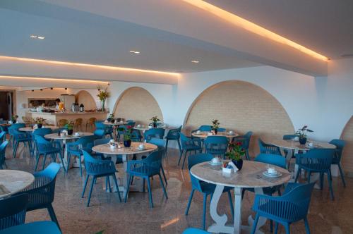 a dining room with tables and blue chairs at Buzios Mar Hotel in Búzios