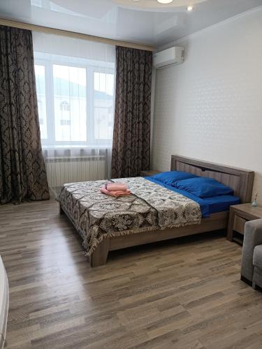 um quarto com uma cama com lençóis azuis e uma janela em 1 комнатная квартира ЖК Альтаир по ул.Байшева 7а em Aqtöbe