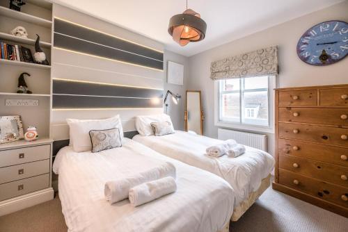 two beds in a bedroom with a clock on the wall at 60 High Street Southwold in Southwold