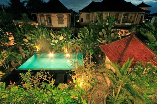 a garden with a swimming pool and some houses at Tanah Semujan Ubud in Ubud