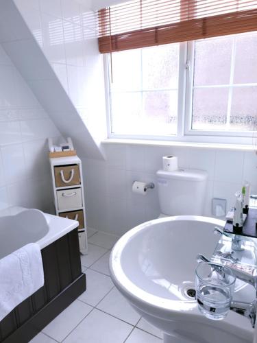 a white bathroom with a sink and a toilet at The Birdham At Bembridge in Bembridge