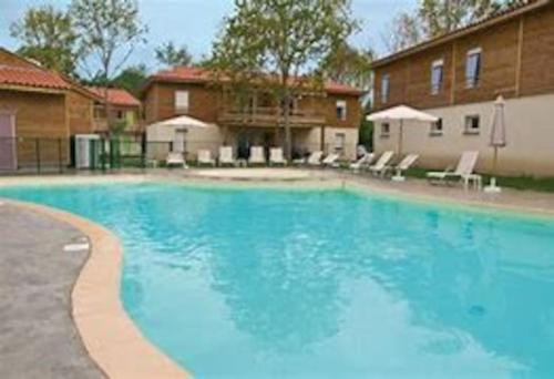 une grande piscine bleue devant une maison dans l'établissement Aureilhan-appartemant 4-6 pp Piscine Cosy en bord lac, à Aureilhan