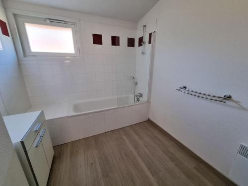 a white bathroom with a tub and a window at La Cabane Aureilhan Appartement 6 pers avec piscine au bord du lac in Aureilhan