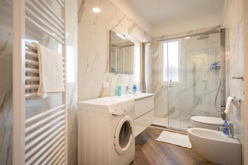 a white bathroom with a washing machine and a sink at Ferrari Apartments Levante in Caorle