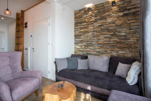 a living room with a couch and a stone wall at Pano Kopaonik Panorama in Kopaonik