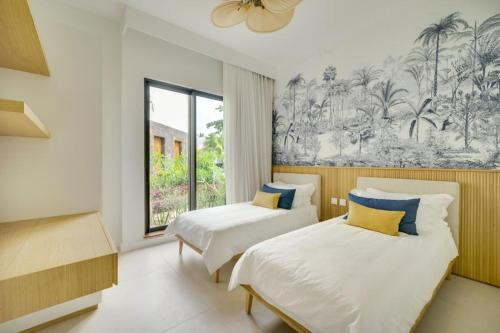 a bedroom with two beds and a large window at Exclusive beachfront apartment in Belle Mare