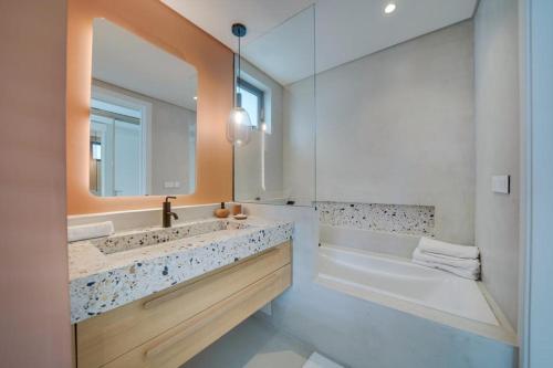 y baño con lavabo, bañera y espejo. en Exclusive beachfront apartment en Belle Mare