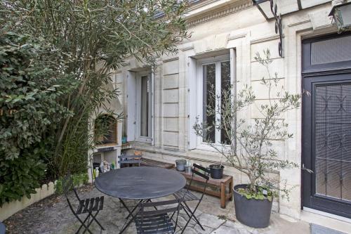 un patio con tavolo e sedie di fronte a un edificio di Exceptional house at the doors of Bordeaux - Welkeys a Le Bouscat