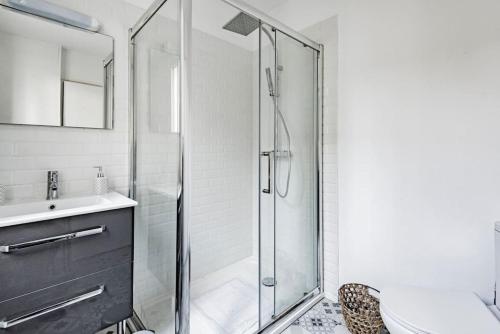 La salle de bains est pourvue d'une douche en verre et d'un lavabo. dans l'établissement LUTON 1, à Reims