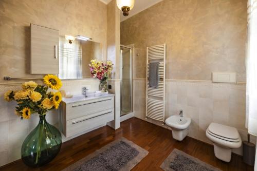ein Badezimmer mit einem Waschbecken, einem WC und einer Vase aus Blumen in der Unterkunft Villa Tullia in Padenghe sul Garda
