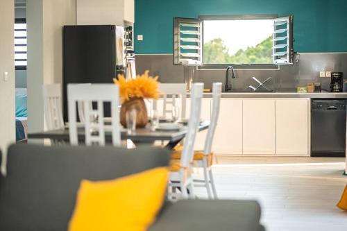 a kitchen with a table and chairs with yellow pillows at VT cottage in Rivière-Pilote