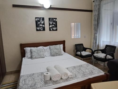 1 dormitorio con 1 cama con toallas y 2 sillas en Aim Furnished Homes in Mtwapa near Beach, en Mtwapa