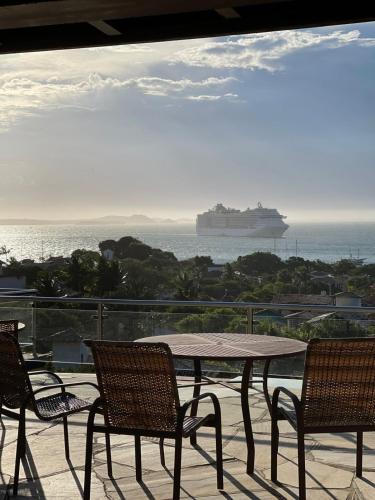 a table and chairs with a cruise ship in the ocean at Casa Espetacular - João Fernandes - NÃO ACEITAMOS PETS in Búzios