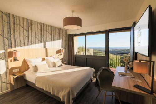 Cette chambre comprend un lit, un bureau et une fenêtre. dans l'établissement Le Bois d'Imbert, à Rocamadour