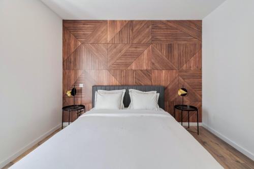 1 dormitorio con 1 cama blanca grande y pared de madera en Golden Setubal, en Setúbal