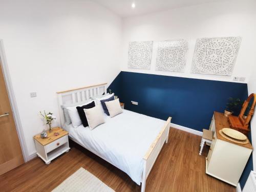 1 dormitorio con cama blanca y pared azul en The Bakery, en Pilling