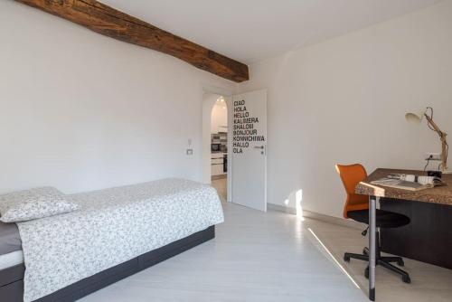 una camera da letto bianca con un letto e una scrivania di Apt in centro storico a due passi dal lago a Cernobbio