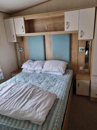 Caravan L16 في مابليتورب: غرفة نوم بسرير بملاءات بيضاء وجدران زرقاء