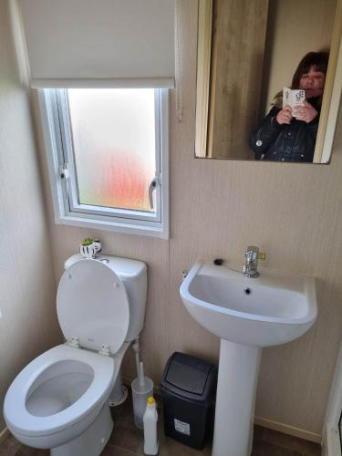 a person taking a picture of a bathroom with a toilet and sink at Caravan L16 in Mablethorpe