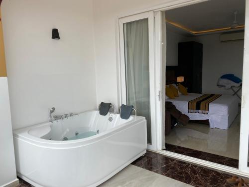 a white bath tub in a room with a bedroom at Cassandra Culture Resort in Sigiriya