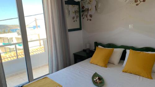 a bedroom with a bed with yellow pillows and a window at D&R Sunshine Apartment in Nea Kydonia