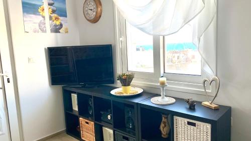 a blue cabinet with a television and a window at D&R Sunshine Apartment in Nea Kydonia