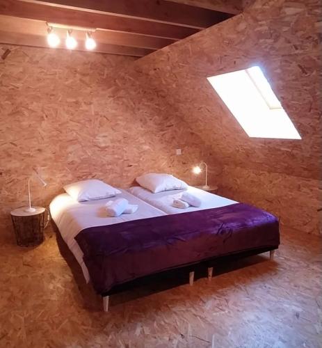 1 dormitorio con 1 cama grande en una pared de piedra en L’Audacieuse, maison atypique, en Aubusson