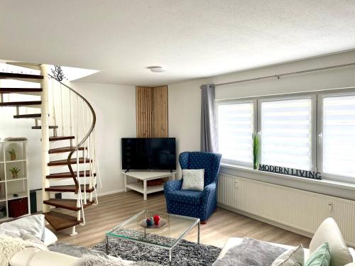 a living room with a spiral staircase and a blue chair at Haus SauerlandLiebe in Schmallenberg