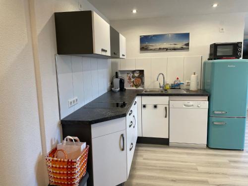 a kitchen with a blue refrigerator and white cabinets at Blumenhof - ERHOLUNG PUR, traumhafte Aussicht in Zell im Wiesental