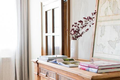 uma mesa com livros e um espelho e um vaso com flores em Casa Perazzolo em Montecchia di Crosara