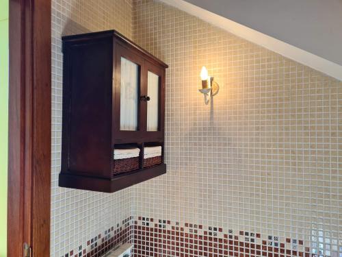 a bathroom with a tiled wall with a cabinet at El ático de la Gorga in Boltaña