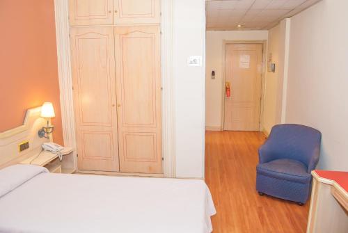 a bedroom with a bed and a blue chair at Ana María in Granada