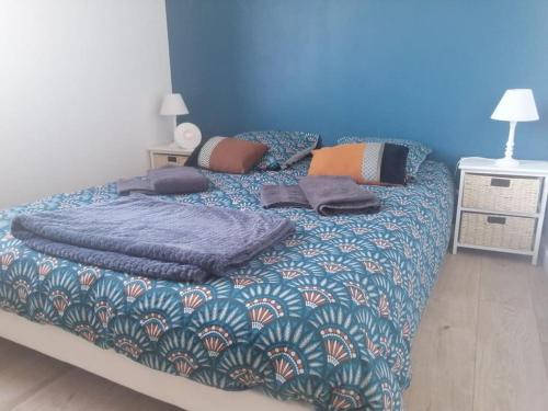 - un lit avec une couverture bleue et des oreillers dans l'établissement Le Courlis, à deux minutes de la plage, à Hauteville-sur-Mer