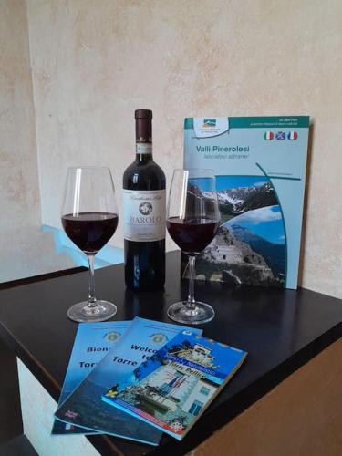 a bottle of wine and two glasses on a table at Casa Vacanze Le tre Sorelle in Torre Pellice