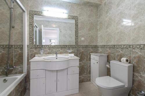 een badkamer met een wastafel, een toilet en een spiegel bij Apartamento King in Vilamoura