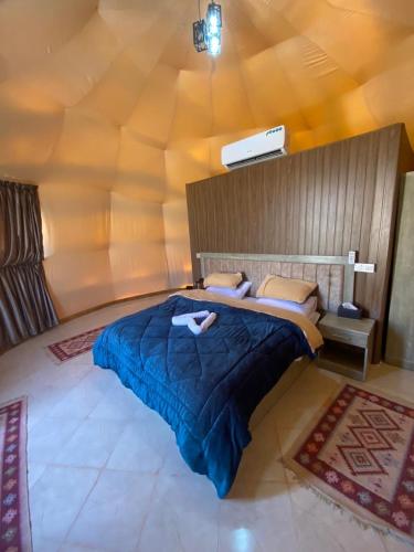 a bedroom with a large bed with a blue blanket at Salma Desert Camp in Wadi Rum