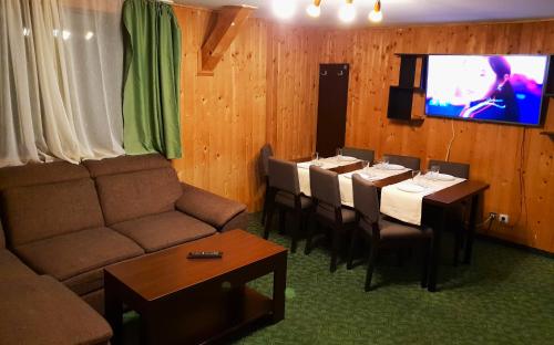 a living room with a couch and tables and a tv at Traveland Boutique Resort Poiana Brasov in Poiana Brasov
